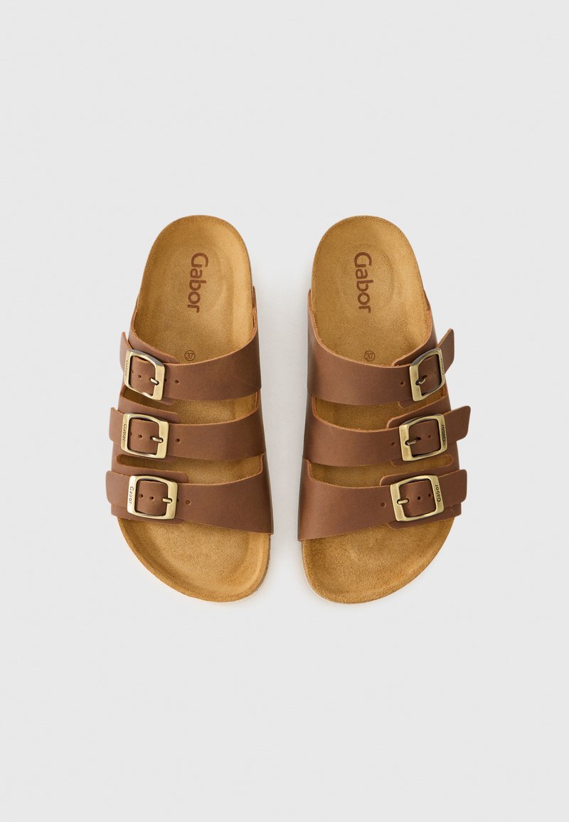 Bruine sandalen met drie verstelbare gespsluitingen en gevoerde voetbedden, plat neergelegd op een witte achtergrond.