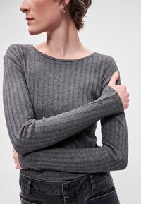 Γκρίζο ριμπ μακρυμάνικο μπλουζάκι με φαρδύ λαιμό και εφαρμοστά μανίκια, φορεμένο με σκούρα τζιν. Λεπτή υφή και διακριτό σχέδιο σε όλη την επιφάνεια.