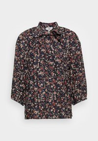 Chemisier bleu marine avec un motif floral rouge, blanc et beige, manches ballon et col avec un nœud.