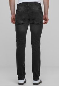 Mustad slim-fit teksad, mis on valmistatud siledast denimist, kahe tagataskuga ja keskmise kõrgusega vöökoht.