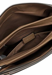 Innenansicht einer braunen Handtasche mit mehreren Reißverschluss- und offenen Fächern, Stofffutter und einem kleinen Lederetikett mit Markenlogo.