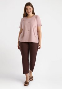 Ljusrosa kortärmad topp med broderade blommor, kombinerad med bruna smala byxor och bruna klacksandaler.