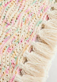 Gebreide dekent in crème met roze, gele en groene accenten, voorzien van een franjerand en een textuur met opengewerkte patroon.