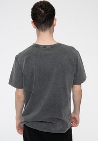 Gray short-sleeve t-shirt with a worn texture, round neckline, and visible stitching details at the collar and hem.
