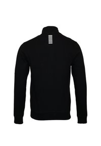 Sudadera negra con cuello alto, mangas largas y rayas horizontales blancas en la parte posterior. Confeccionada con una tela suave y lisa.