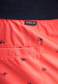 Korallfarbene Shorts mit einem marineblauen Bund, versehen mit kleinen schwarzen Hummermustern. Enthält eine Gesäßtasche und ein Etikett mit der Aufschrift "PETROL IND."