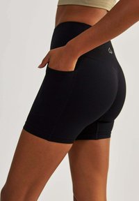 Black athletic shorts with a fitted design, made from stretchy fabric, featuring side pockets and contrasting seam details.