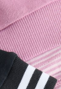 Tela de punto rosa con textura acanalada y detalle de rayas; una sección negra con rayas blancas debajo. Material suave y casual.