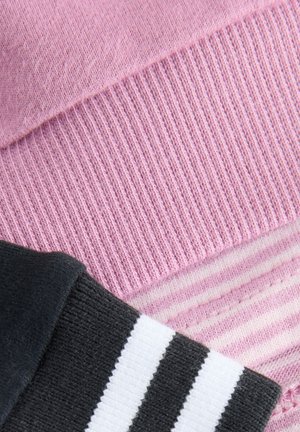 Tissu tricoté rose avec une texture côtelée et un détail rayé ; une section noire avec des rayures blanches en dessous. Matière douce et décontractée.