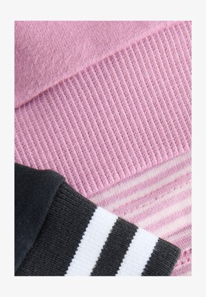 Ružičasta pletena tkanina s rebrastom teksturom i prugastim detaljem; crni dio s bijelim prugama ispod. Meki, ležerni materijal.