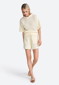 Lightweight knitted two-piece set in cream, featuring a loose short-sleeve top and matching shorts with an elastic drawstring waist.