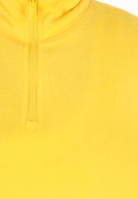 Gul fleece sweatshirt med høj krave og halv længde lynlås. Blød tekstur og glat finish, med syninger på kraven.