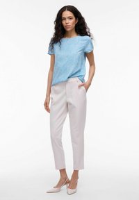 Ljusblå kortärmad topp med prickmönster, tillsammans med beigefärgade slim-fit byxor och ljusrosa högklackade skor med spetsiga tår.