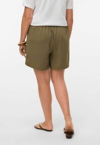 Olivgröna shorts med elastisk midja, slät textur och avslappnad passform, kombinerat med en vit t-shirt och svarta sandaler.