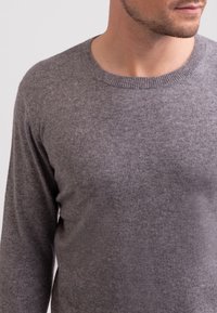 Grauer Langarmpullover aus weichem, strukturiertem Stoff mit Rundhalsausschnitt. Verfügt über einen gerippten Kragen und eine taillierte Passform.