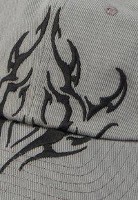 Șapcă de baseball din material gri, cu broderie neagră tribală în formă de flacără pe panoul din față și pe cozoroc.