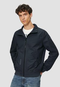 Marine bomberjack met een opstaande kraag, frontzak met rits, twee zijzakken en geribbelde manchetten. Gemaakt van glad, lichtgewicht materiaal.