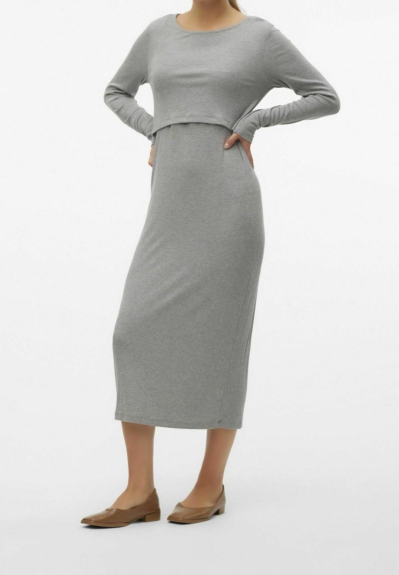 Grå klänning med lång ärm och en kortad överdel som går rakt ner till kjolen. Slät tyg med en subtil textur. Återfinns med bruna platta skor.