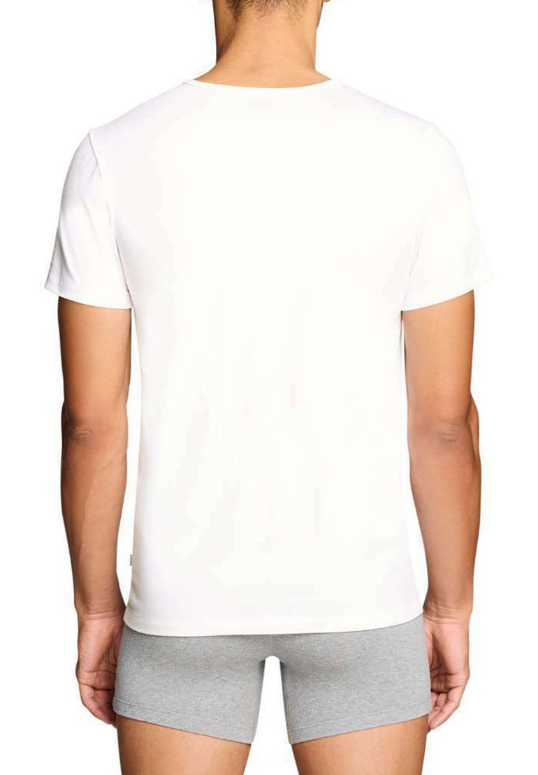 Homme vu de dos portant un t-shirt blanc uni à manches courtes et un short ajusté gris clair sur un fond blanc.