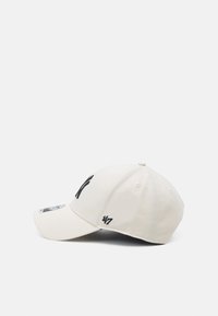 Beige színű baseball sapka fekete hímzett logóval és varrással. Az ívelt karima és a szellőző lyukak jellemzik. A márka logója az oldalon található.