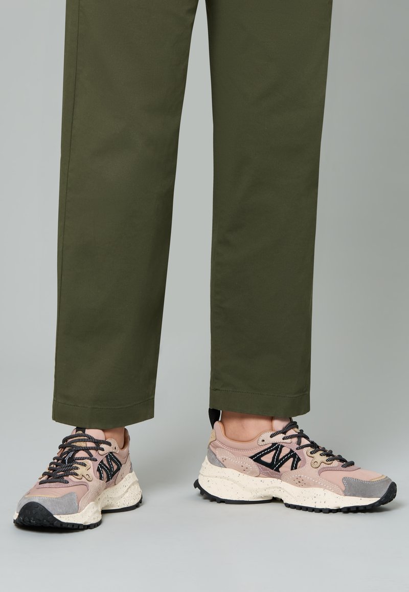Sneaker leggera con tomaia rosa e grigia, lacci neri e suola intermedia bianca maculata. Presenta una suola in gomma testurizzata per una buona aderenza.