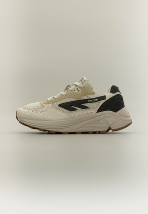 Svetlo bež in črn športni copat z mrežico in semišem, debelim podplatom in napisom "SHADOW" na stranskem panelu.