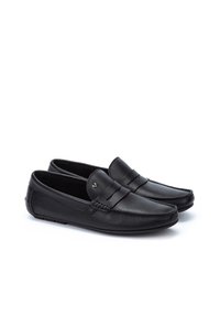 Mocasines de piel negra con un acabado suave, que presentan un detalle de costura en la parte delantera y un pequeño logo en la correa. Diseño clásico, estilo de fácil puesta.