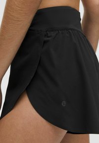 Fustă sport neagră cu talie înaltă și slituri laterale, realizată din material ușor; dispune de un logo pe tivul inferior.