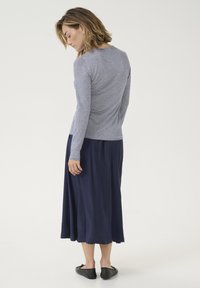 Hosszú sötétkék szoknya, amelyhez egy testhezálló, csíkos, hosszú ujjú felső tartozik. A felső kerek nyakkivágással és fodros részlettel rendelkezik a hátsó részen.