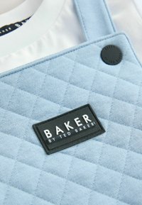 Svijetloplavi prešani materijal s pravokutnom crnom etiketom na kojoj piše "BAKER BY TED BAKER." Sadrži akcent crnog gumba u obliku kruga.
