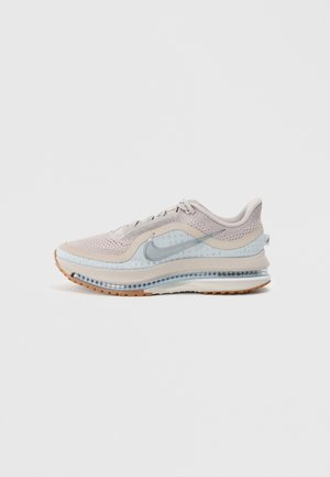 Chaussure de course Nike beige clair et blanche avec tige en mesh, unité Air visible et semelle extérieure en caoutchouc naturel, présentée de profil sur fond blanc.