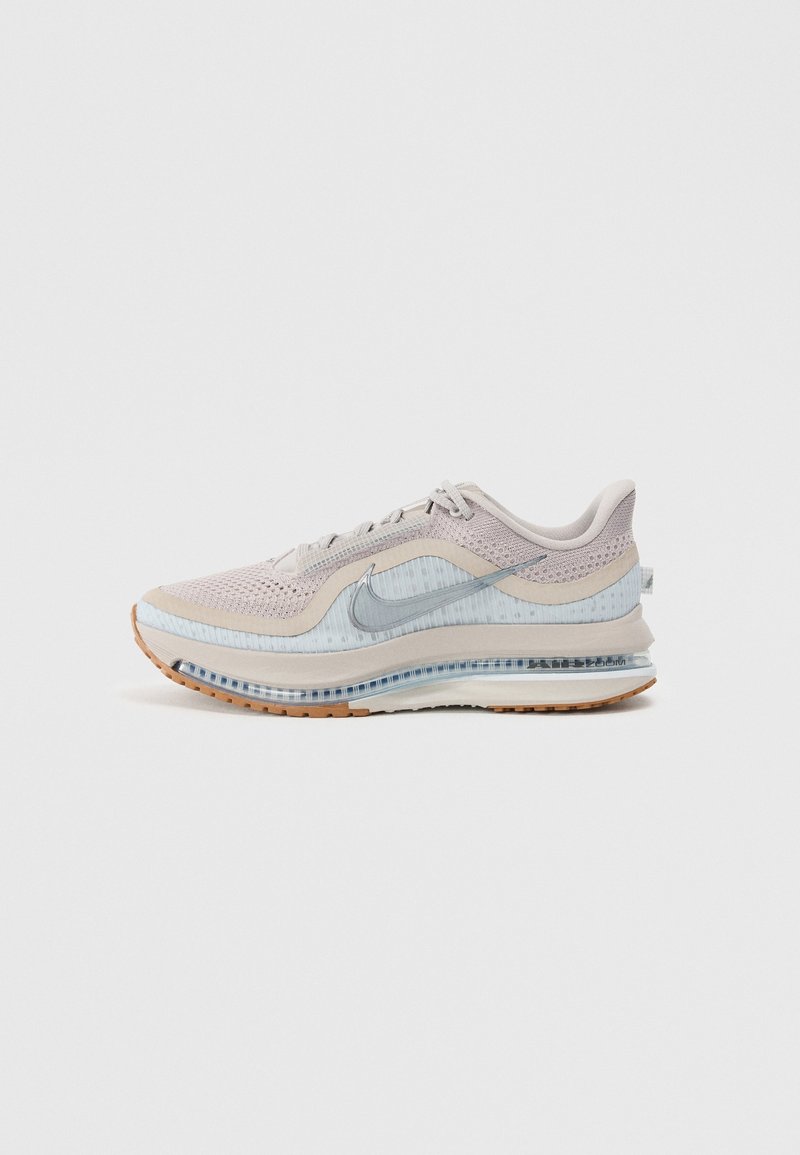 Chaussure de course Nike beige clair et blanche avec tige en mesh, unité Air visible et semelle extérieure en caoutchouc naturel, présentée de profil sur fond blanc.