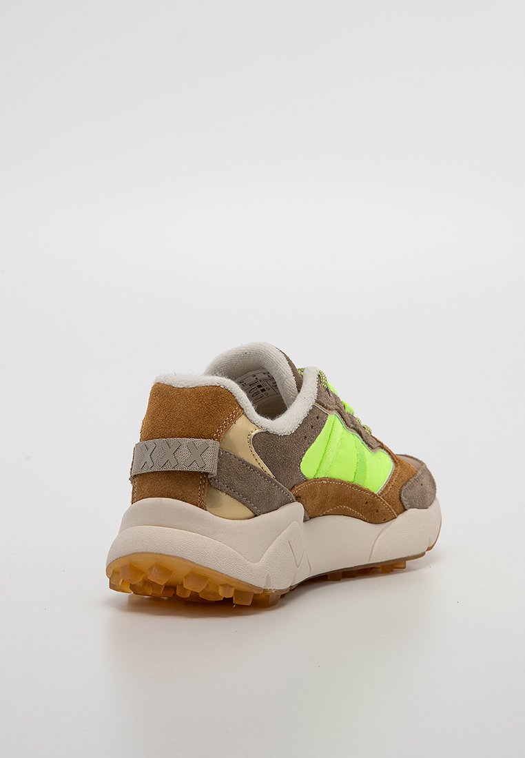 Zapatilla con ante marrón, paneles en beige y verde neón, cuello acolchado blanco y suela texturizada beige, mostrada desde un ángulo trasero sobre fondo blanco.