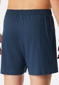 Boxers bleus pour homme avec un motif géométrique texturé, une taille élastique et une coupe décontractée, fabriqués en tissu doux et respirant.