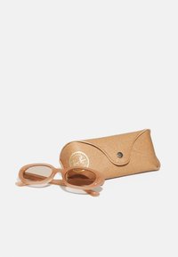 Ochelari de soare Ray-Ban cu o ramă din plastic fin, de culoare maro deschis, și lentile maro, însoțiți de un cusuor texturat de culoare bej cu închidere tip clapetă.