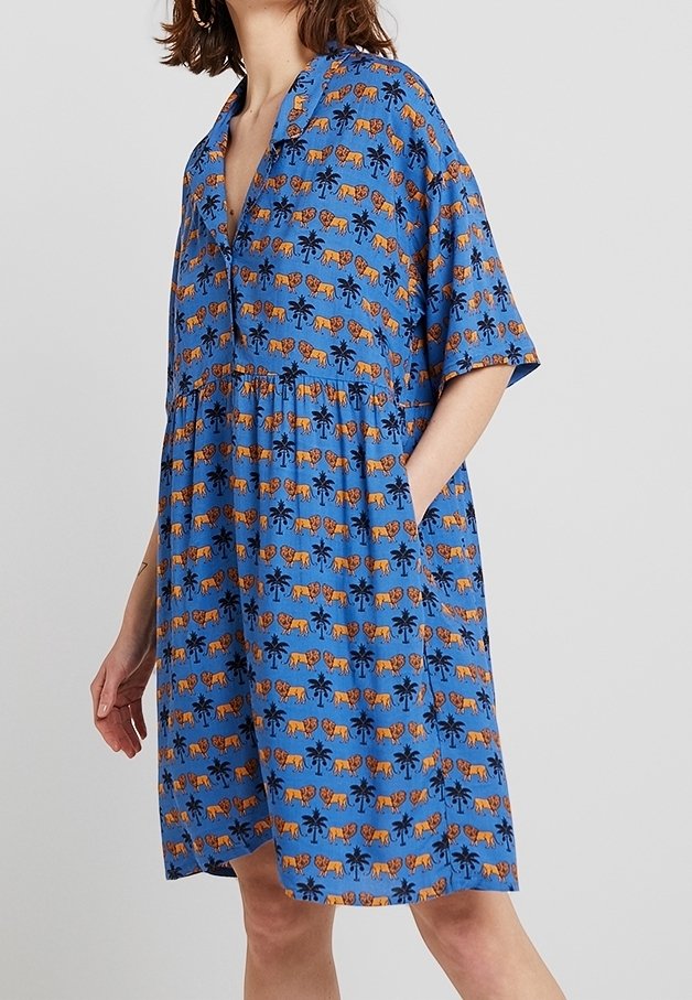Modré šaty s límečkem, krátkými rukávy a nařaseným pasem. Vzor obsahuje oranžové tygři a černé palmy. Dvě boční kapsy.