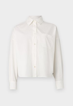 Chemise blanche courte à boutons avec un col classique, des manches longues, une poche poitrine unique et un design minimaliste, dotée d'une texture de tissu douce.
