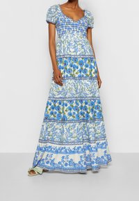 Maxi šaty z lehkého materiálu s květinovým vzorem v modré a zelené barvě, s nařaseným živůtkem, krátkými nafouklými rukávy a splývavým lemem.