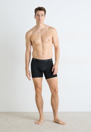 Black boxer briefs with a soft waistband featuring white logo text. The fabric appears smooth and fitted, offering a tailored look.