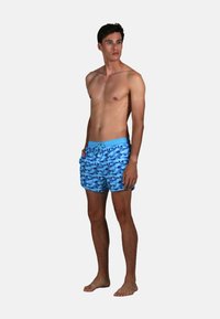 Shorts de bain bleus avec un motif de vagues, taille élastique et cordon de serrage. Fabriqués en tissu léger, idéaux pour la plage.