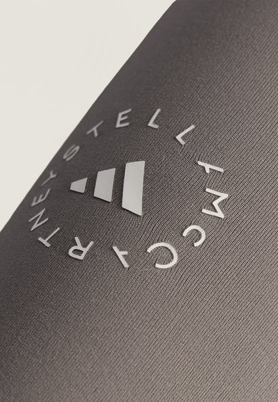Close-up of a gray textured fabric with a circular logo reading "STELLA MCCARTNEY" around three ascending white bars.