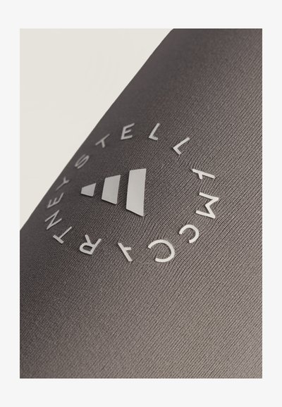 Close-up of a gray textured fabric with a circular logo reading "STELLA MCCARTNEY" around three ascending white bars.