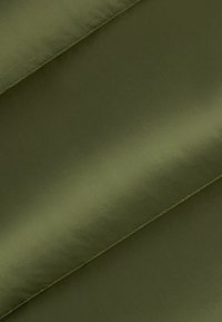 Tessuto verde oliva con finitura lucida, caratterizzato da trame sottili e linee fluide, piegato ad angolo. Cuciture a vista.