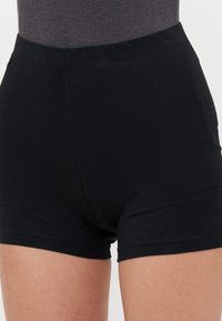 Black cotton shorts with a smooth finish, high waistband, and mid-thigh length. Plain design, no visible patterns or hardware details.