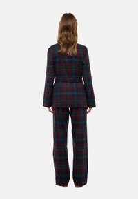 Ensemble de pyjama à carreaux en vert foncé et bordeaux, avec une taille ceinturée, des manches longues et un pantalon évasé. Tissu doux et texturé.