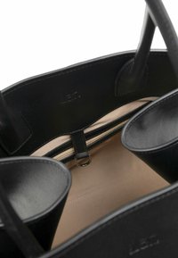 Czarna skórzana torebka z beżowym wnętrzem, wyposażona w dwie otwarte kieszenie i przegrodę na zamek, gładką fakturę oraz wzmocnione uchwyty.