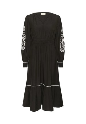 Fekete, hosszú ujjú ruha, V-nyakkivágással és ráncolt derékkal. Fehér hímzett minták díszítik az ujjakon és a szegésen. Szélesedő alj.