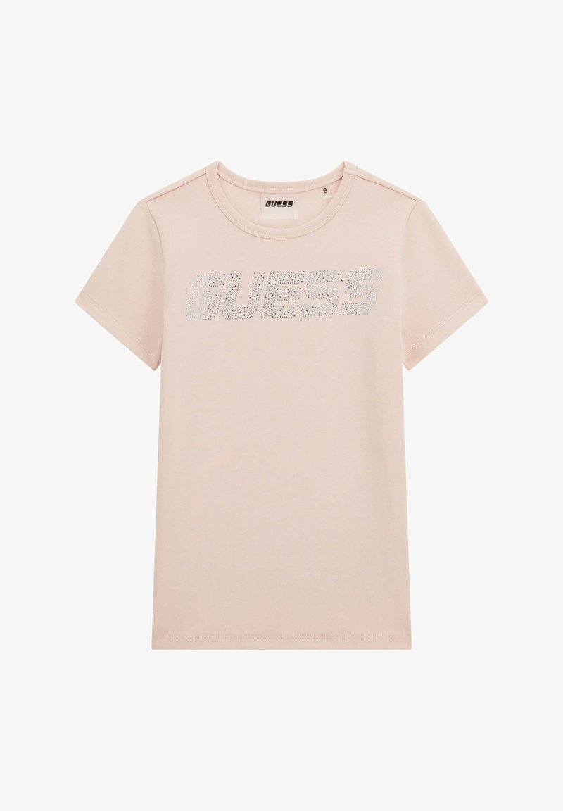 Vaaleanpunainen puuvillapaita, jossa on lyhyet hihat ja joka on varustettu kimaltelevalla "GUESS" -logolla hopeanvärisistä strasseista rinnassa. Pyöreä kaula-aukko.