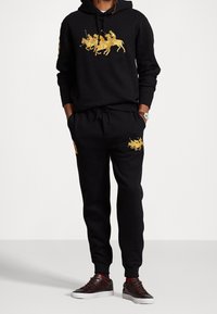 Set di felpa nera e pantaloni jogger realizzato in misto cotone, con ricamo di un giocatore di polo dorato sulla parte anteriore e dettagli abbinati sui pantaloni jogger.