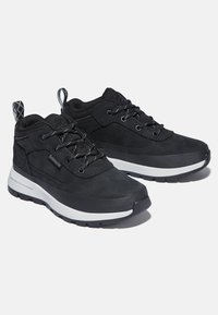 Zapatillas deportivas negras de cuero y malla, con un cuello acolchado, diseño de cordones, suela texturizada y media suela blanca.